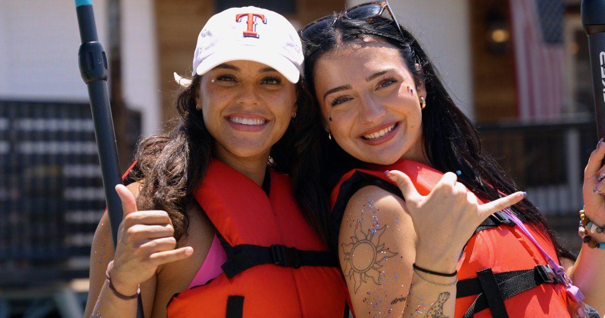 Two smiling friends in life jackets throwing shakas before a group paddle