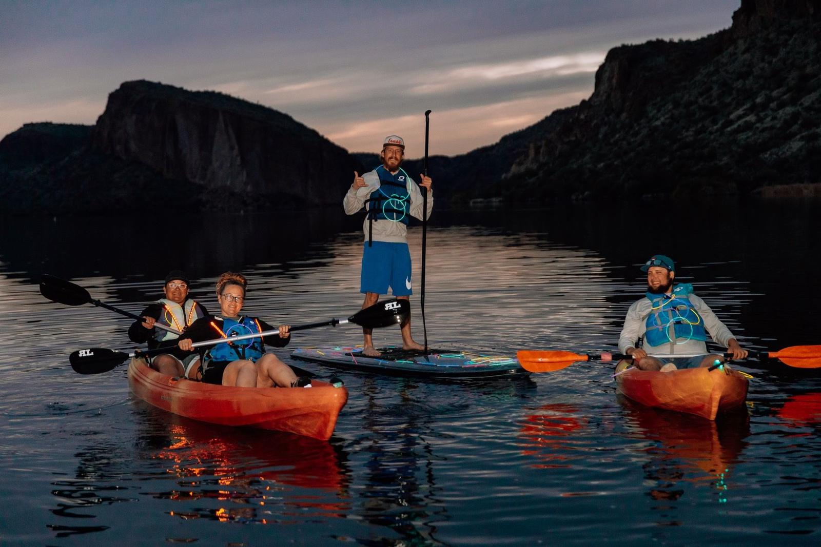 Kayakers and paddleboarders on Canyon Lake after dark