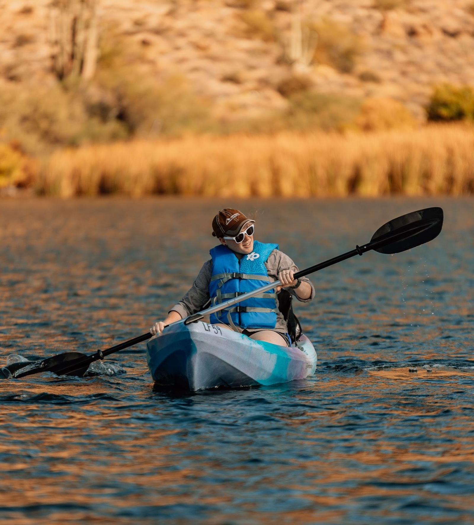 Kayaker paddling past golden reeds at Canyon Lake